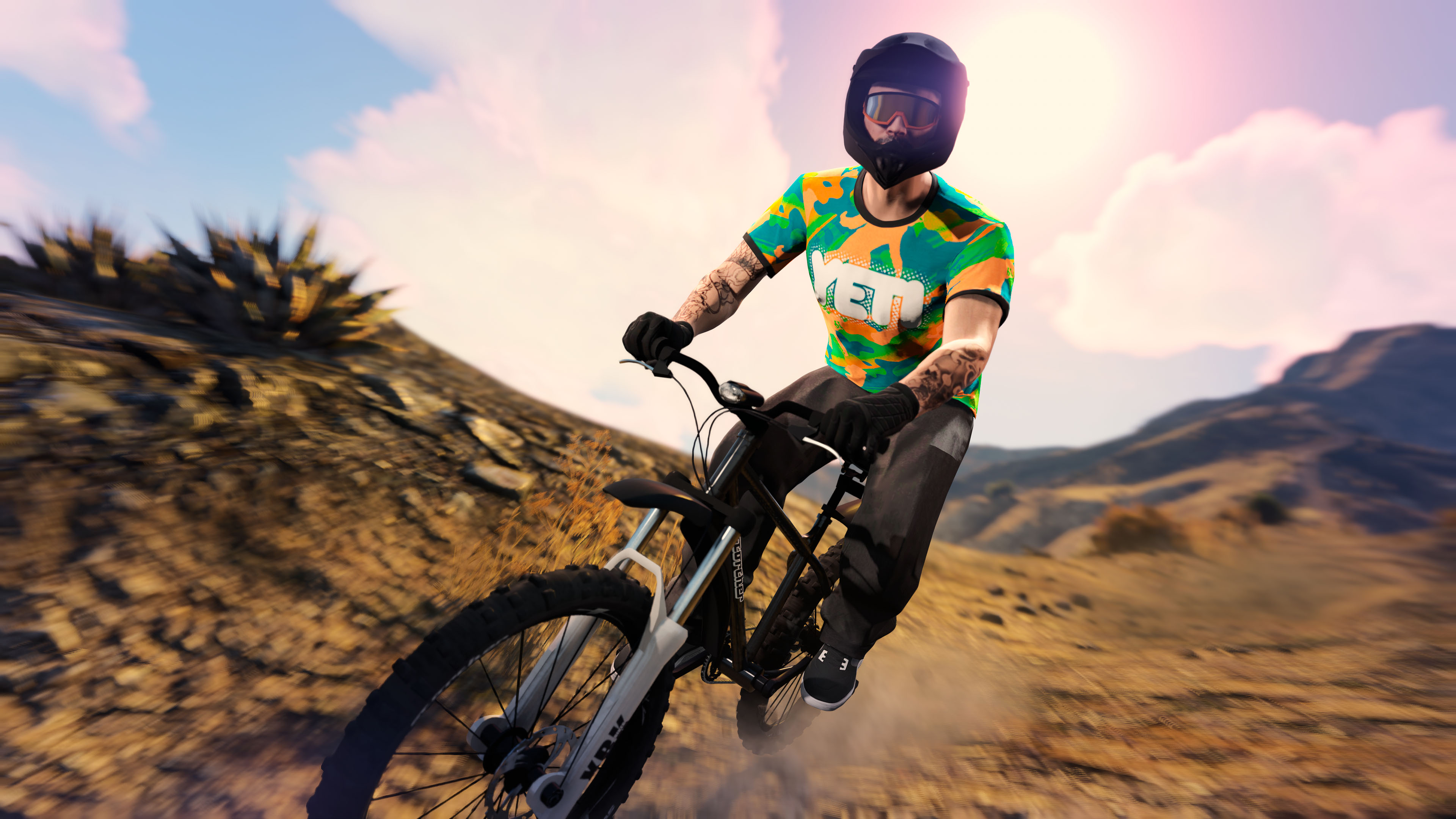 A GTA Online character wearing the Orange Camo Yeti Tee rides an off-road bicycle down a mountain. 