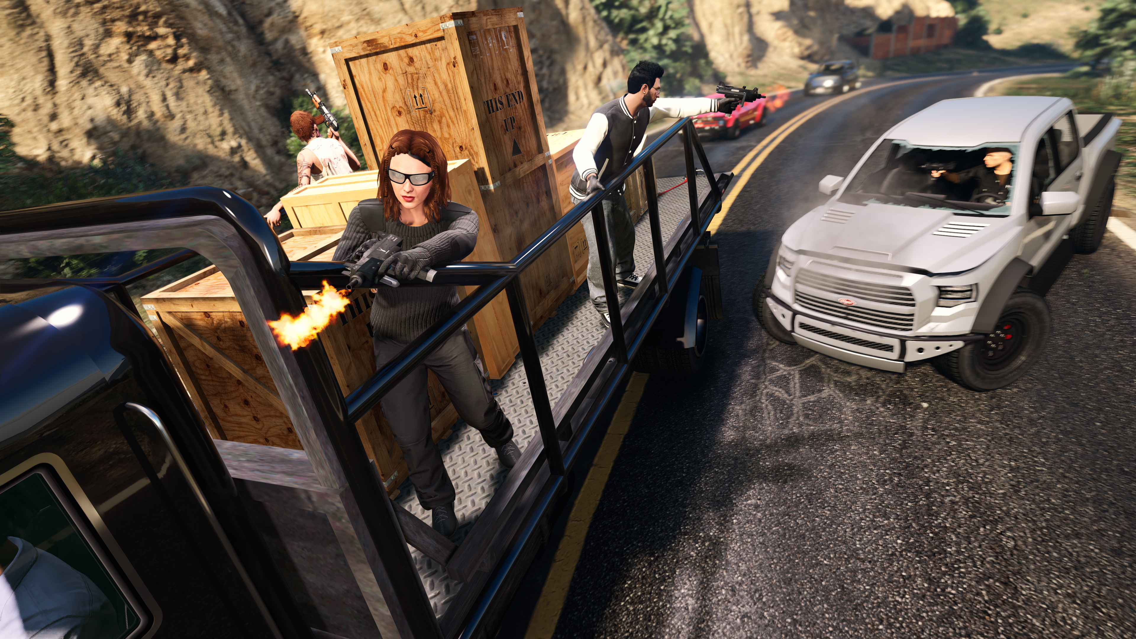 Three GTA Online characters on the back of a truck shoot at pursuing vehicles. 