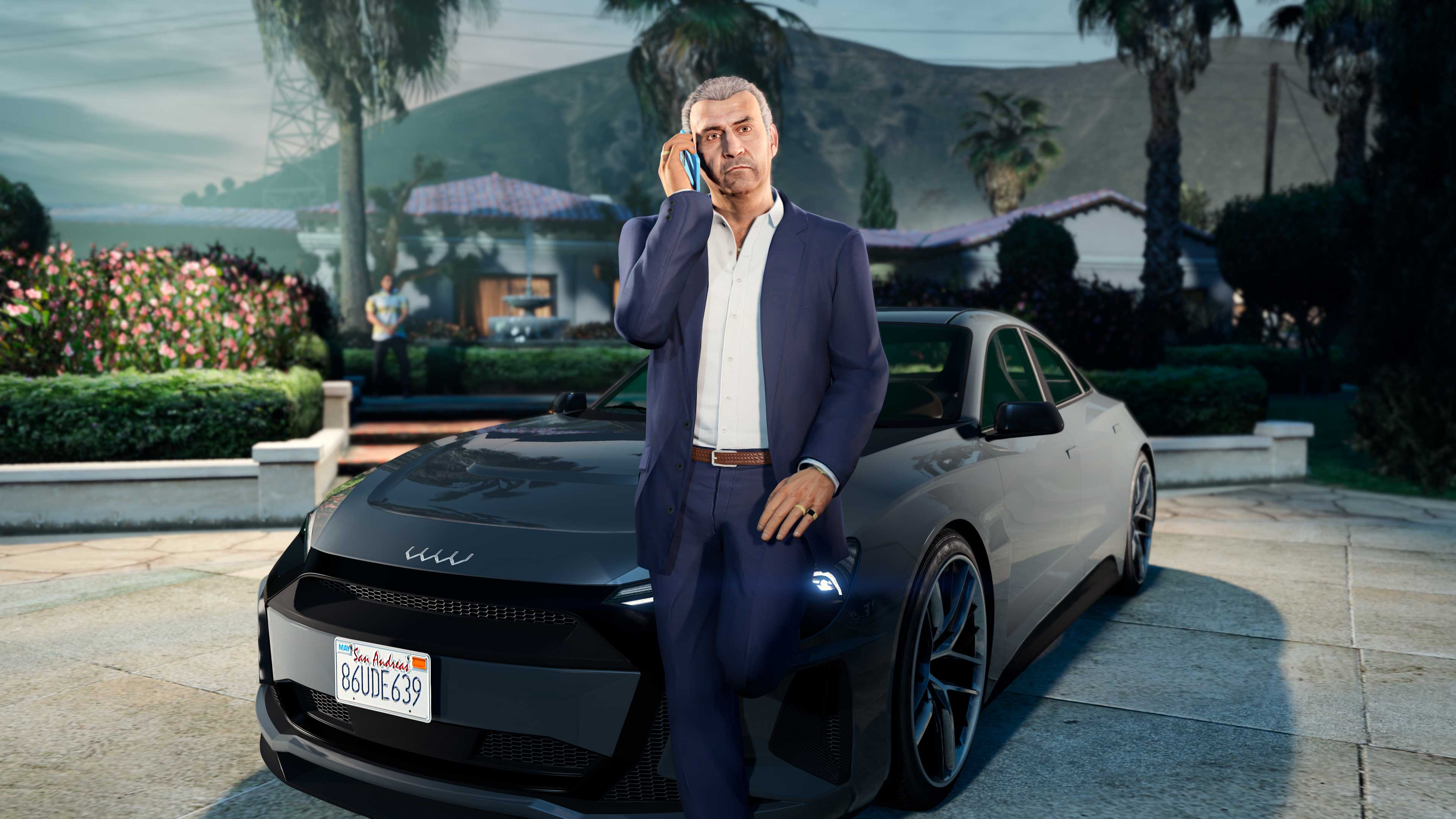 Martin Madrazo leans against a black Omnis e-GT car while talking on a phone.
